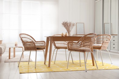 Photo of Dining room interior with wooden table and wicker chairs