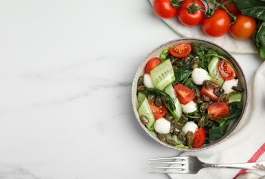 Photo of Salad with vegetables, capers and mozzarella in bowl on white marble table, flat lay. Space for text