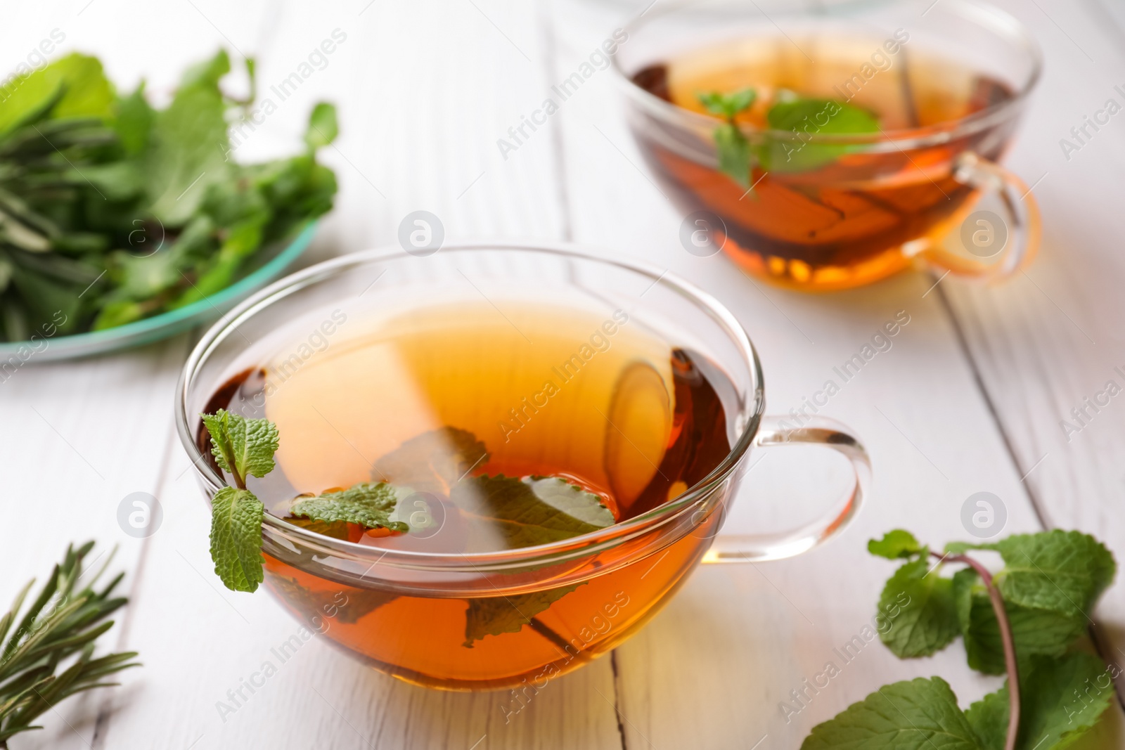 Photo of Aromatic herbal tea with mint and rosemary on white wooden table