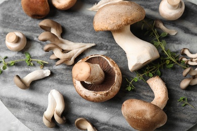 Photo of Fresh wild mushrooms on marble board, closeup view