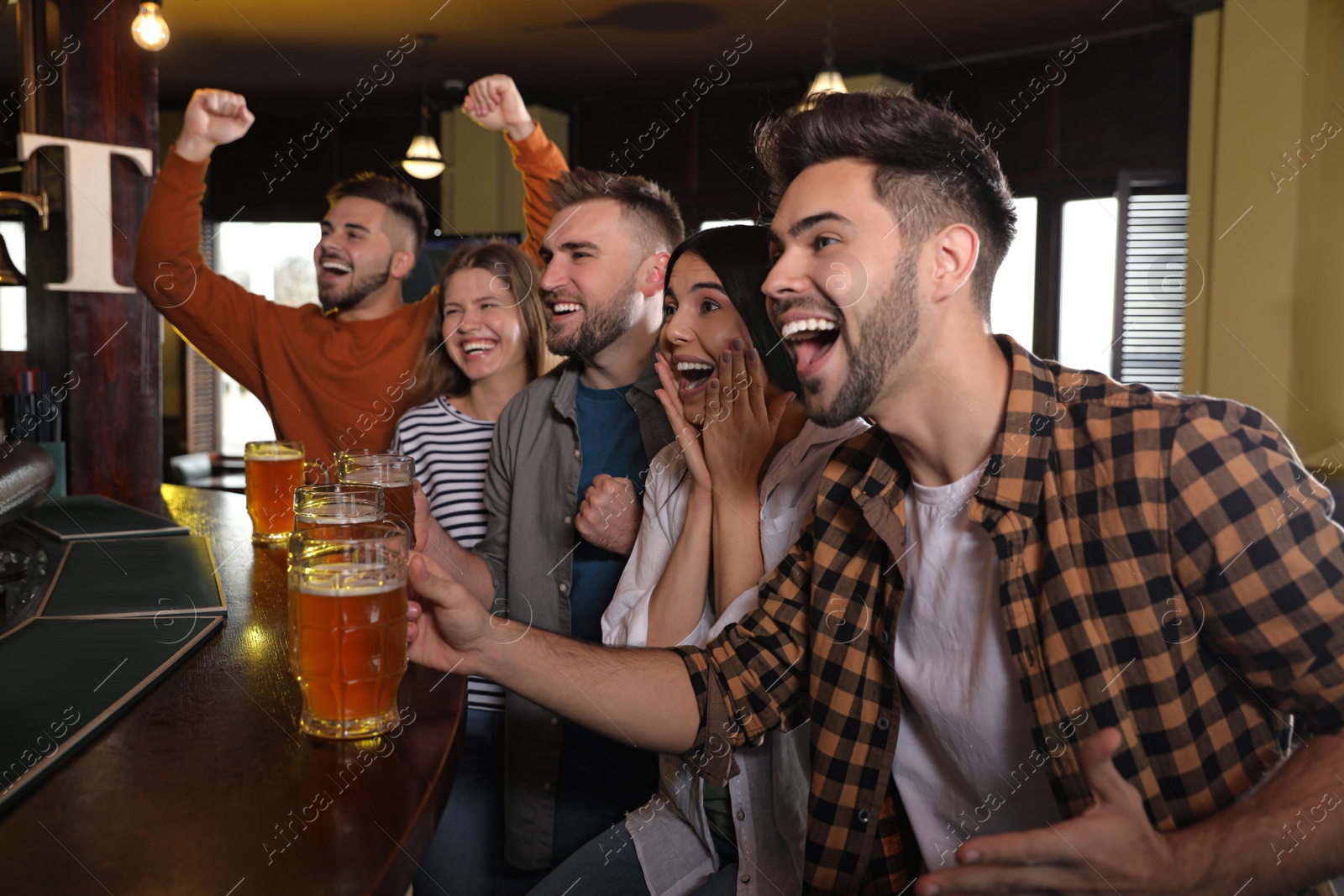 Photo of Group of friends watching football in sport bar