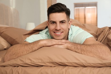 Man lying in bed with brown linens at home