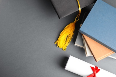 Photo of Flat lay composition with graduation hat and student's diploma on grey background, space for text