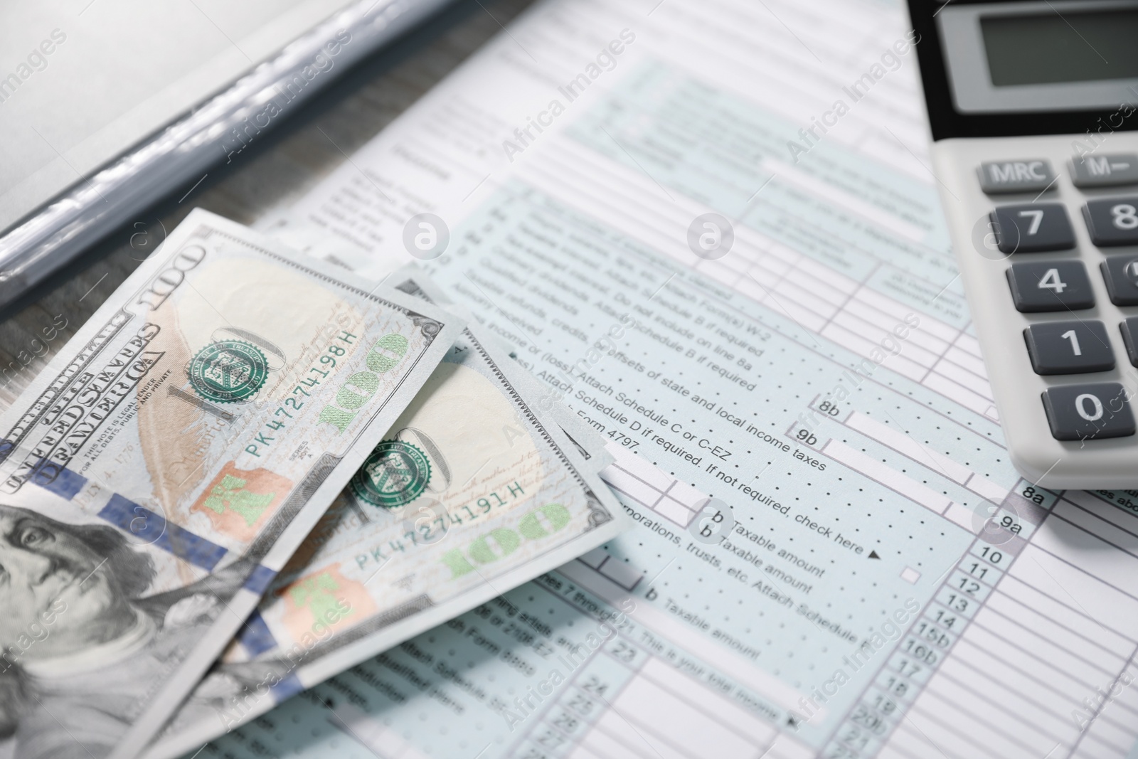 Photo of Payroll. Tax return form, calculator and dollar banknotes on table, selective focus