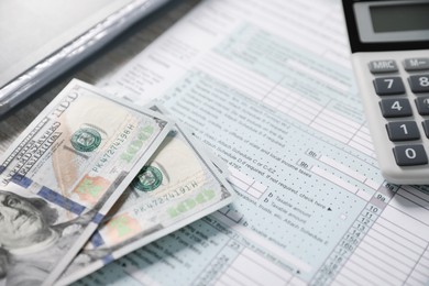 Photo of Payroll. Tax return form, calculator and dollar banknotes on table, selective focus