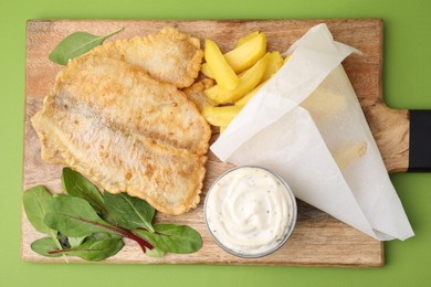 Photo of Delicious fish and chips with tasty sauce and mangold on green table, top view