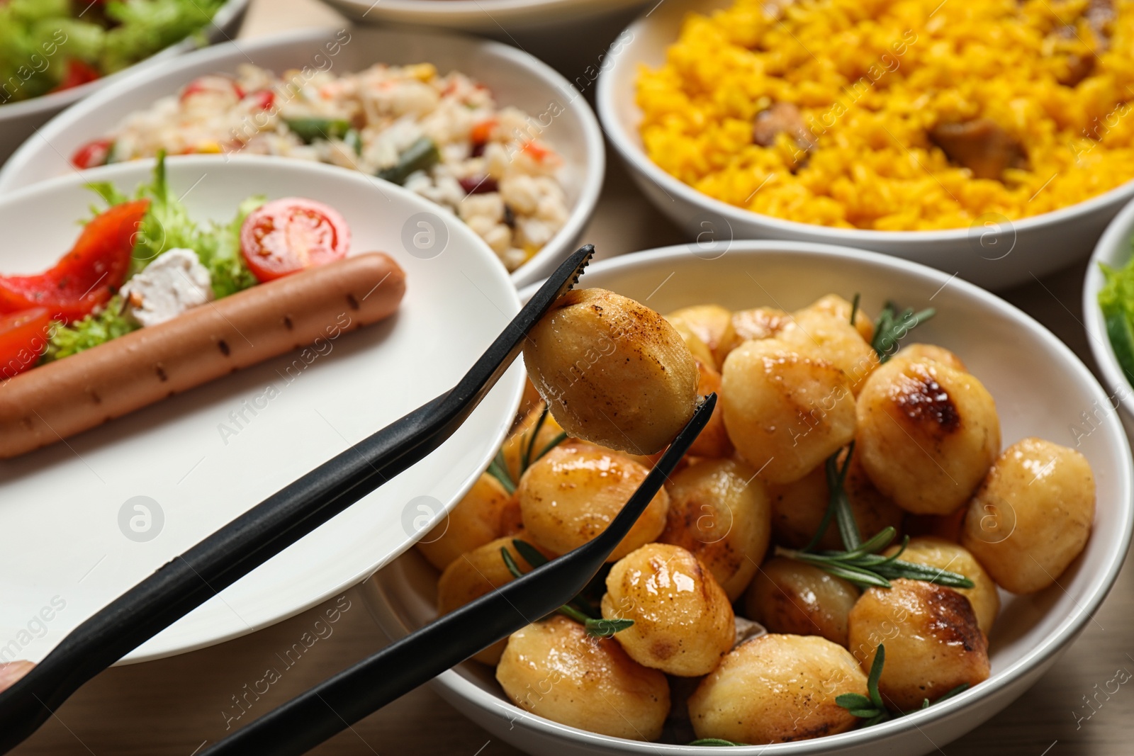 Photo of Taking roasted potato from buffet table, closeup