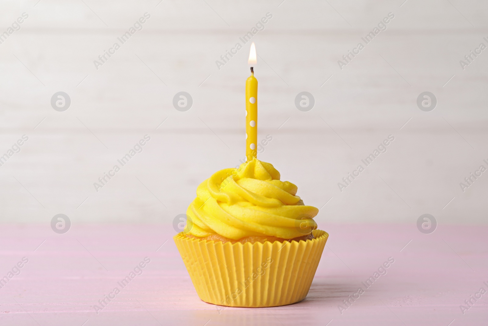 Photo of Delicious birthday cupcake with cream and burning candle on pink table