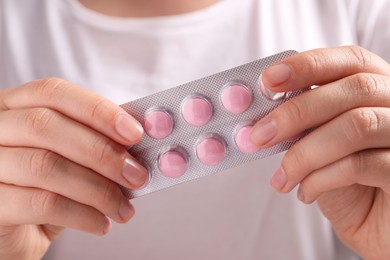 Photo of Woman holding blister of pink pills, closeup