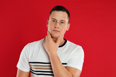 Photo of Handsome young man posing on red background