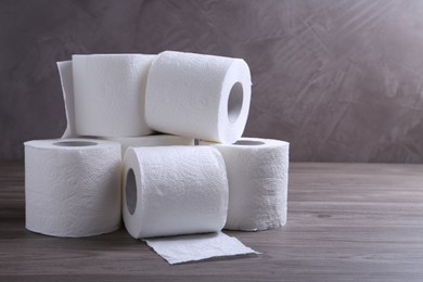 Photo of Soft toilet paper rolls on wooden table. Space for text