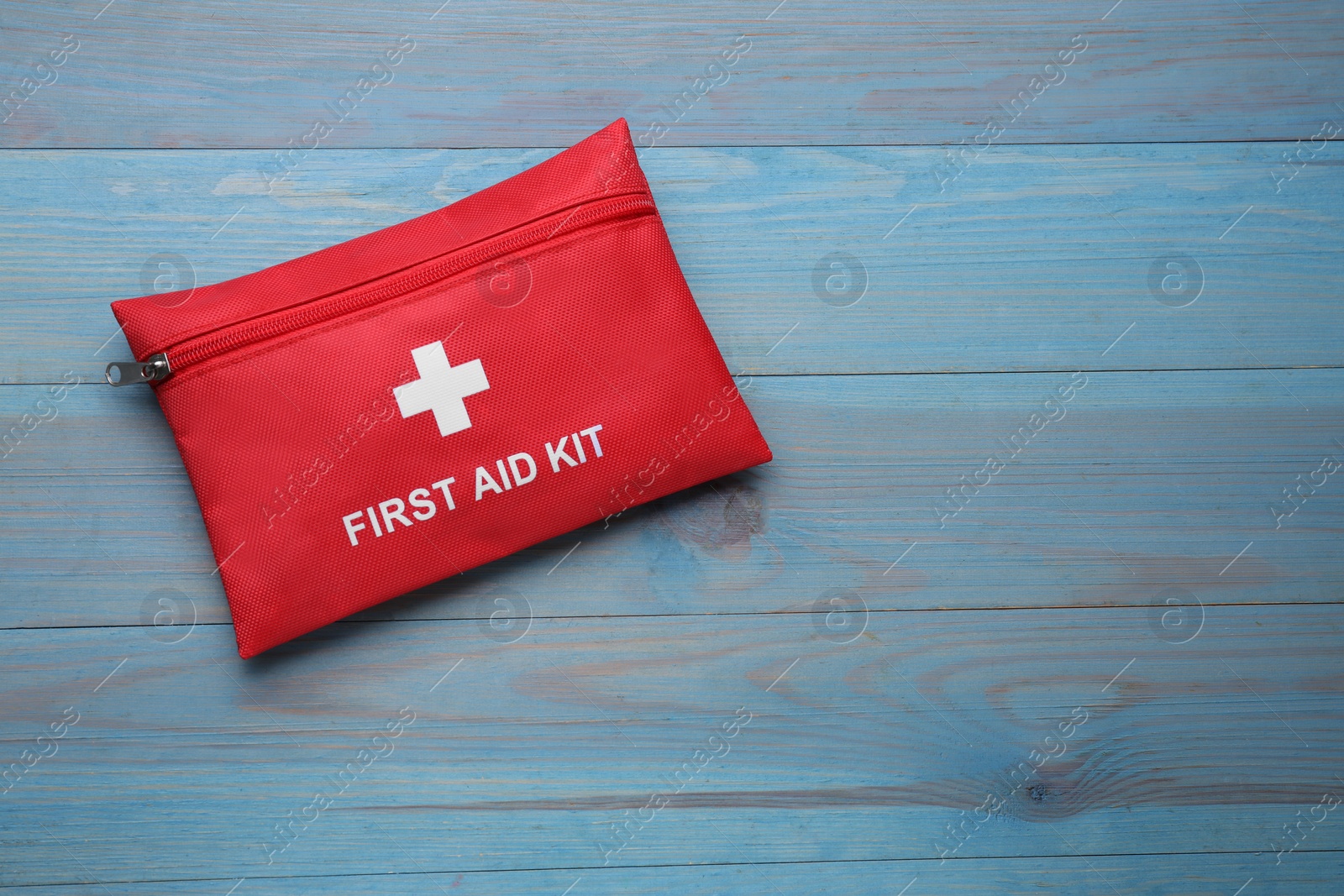 Photo of Medicine bag on blue wooden table, top view with space for text. First aid kit