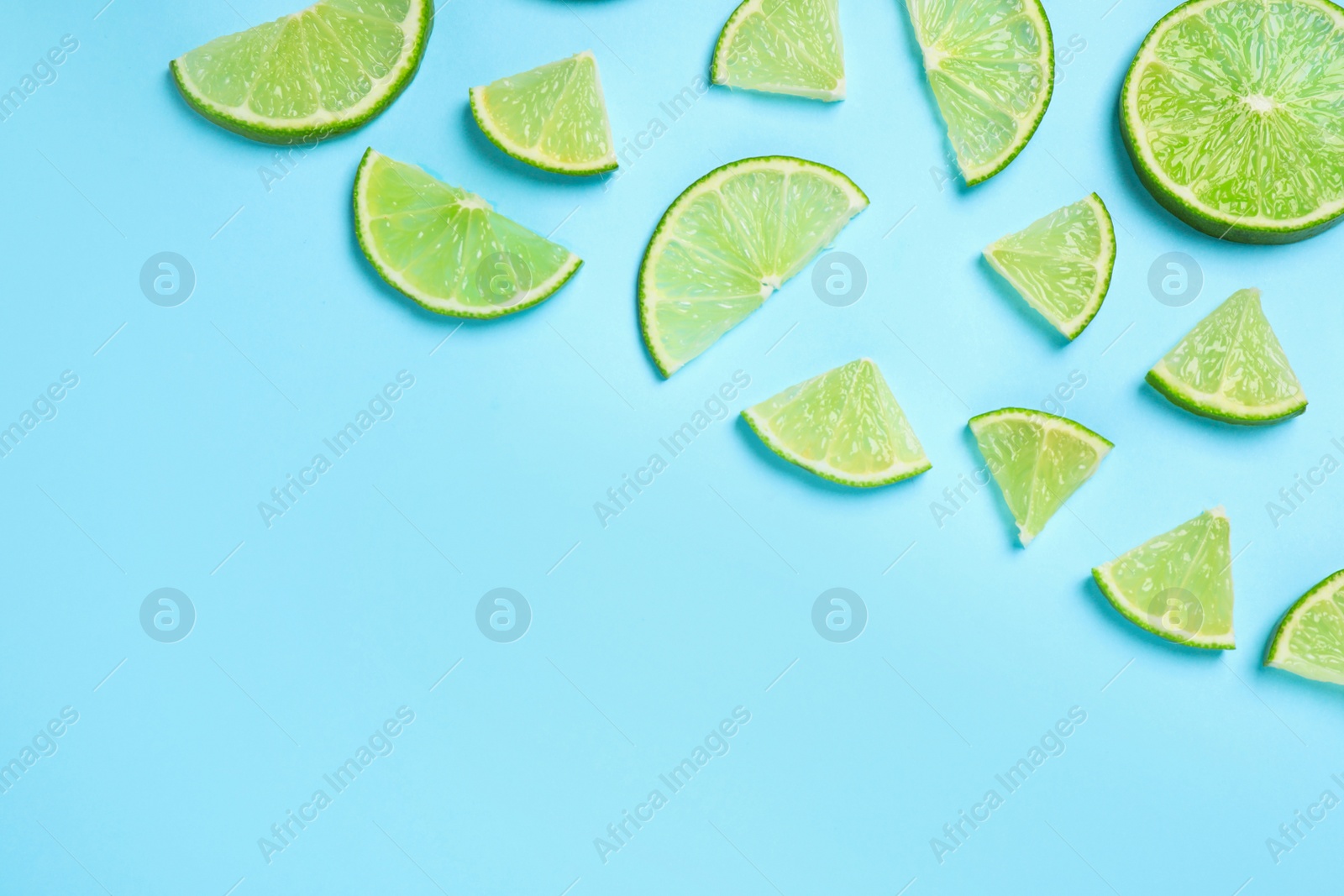 Photo of Juicy fresh lime slices on light blue background, flat lay. Space for text