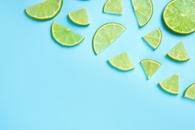 Photo of Juicy fresh lime slices on light blue background, flat lay. Space for text