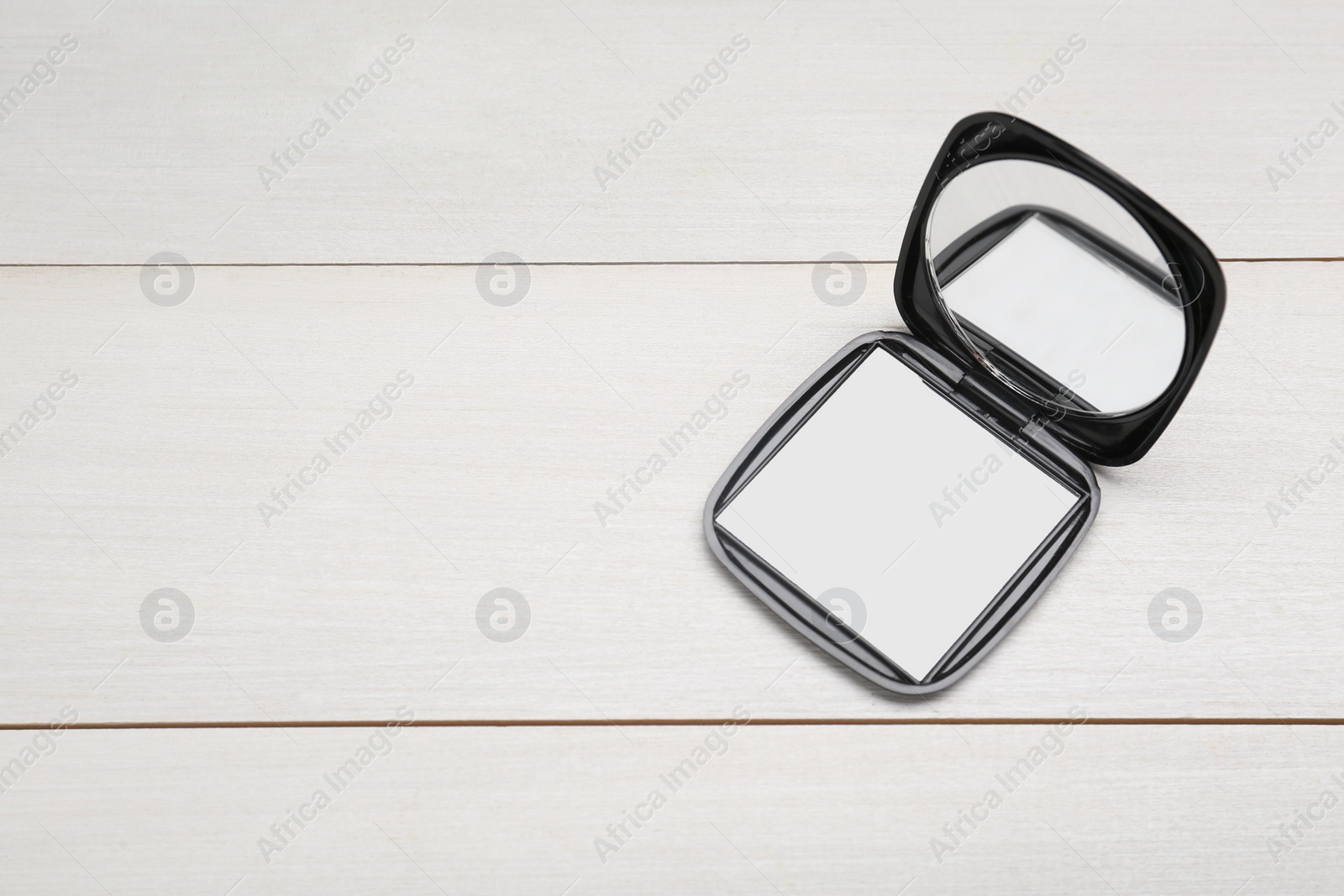 Photo of Stylish cosmetic pocket mirror on white wooden table, top view. Space for text