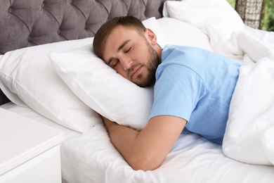 Young handsome man sleeping in bed at home. Early morning