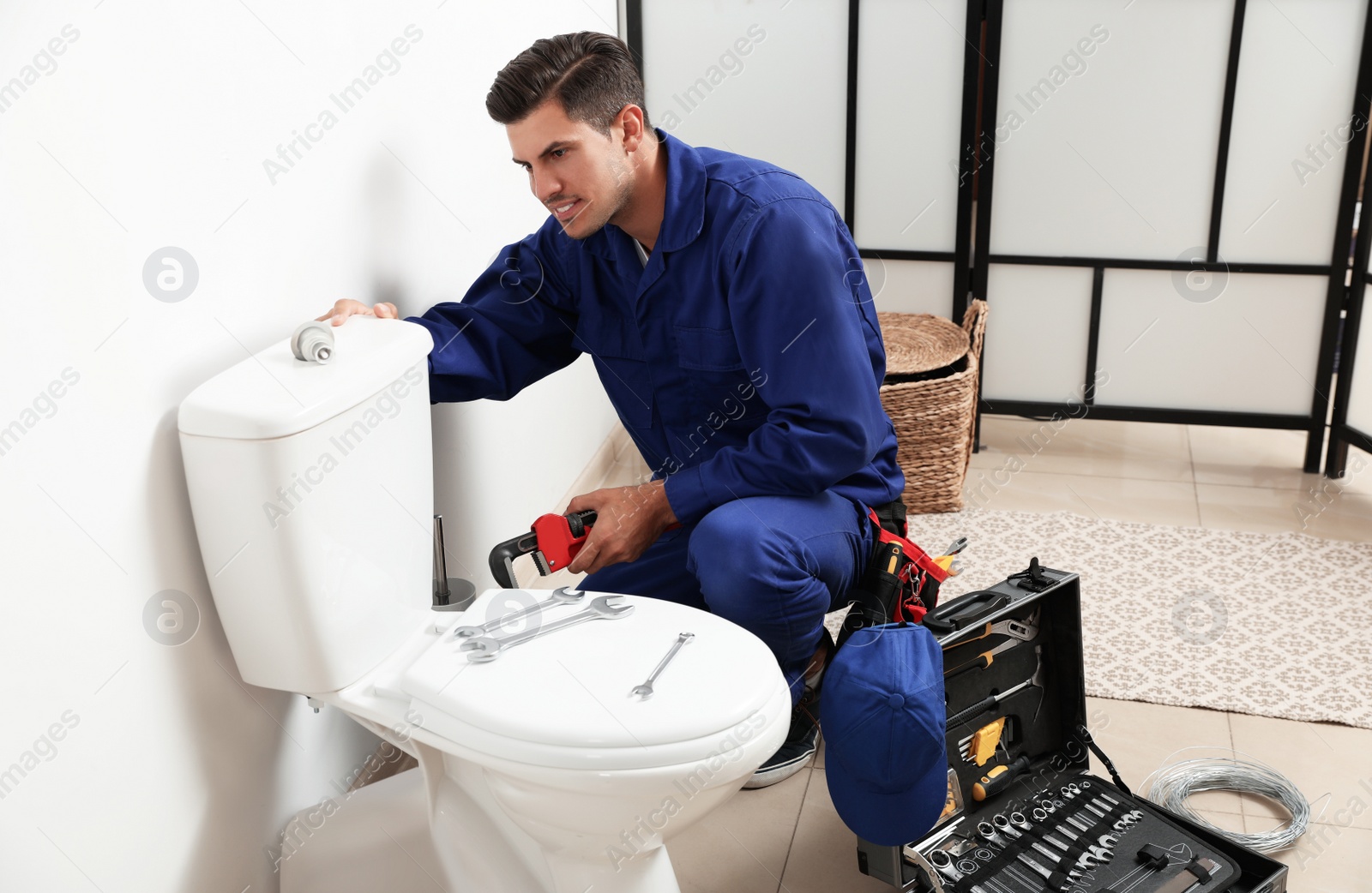 Photo of Professional plumber working with toilet bowl in bathroom