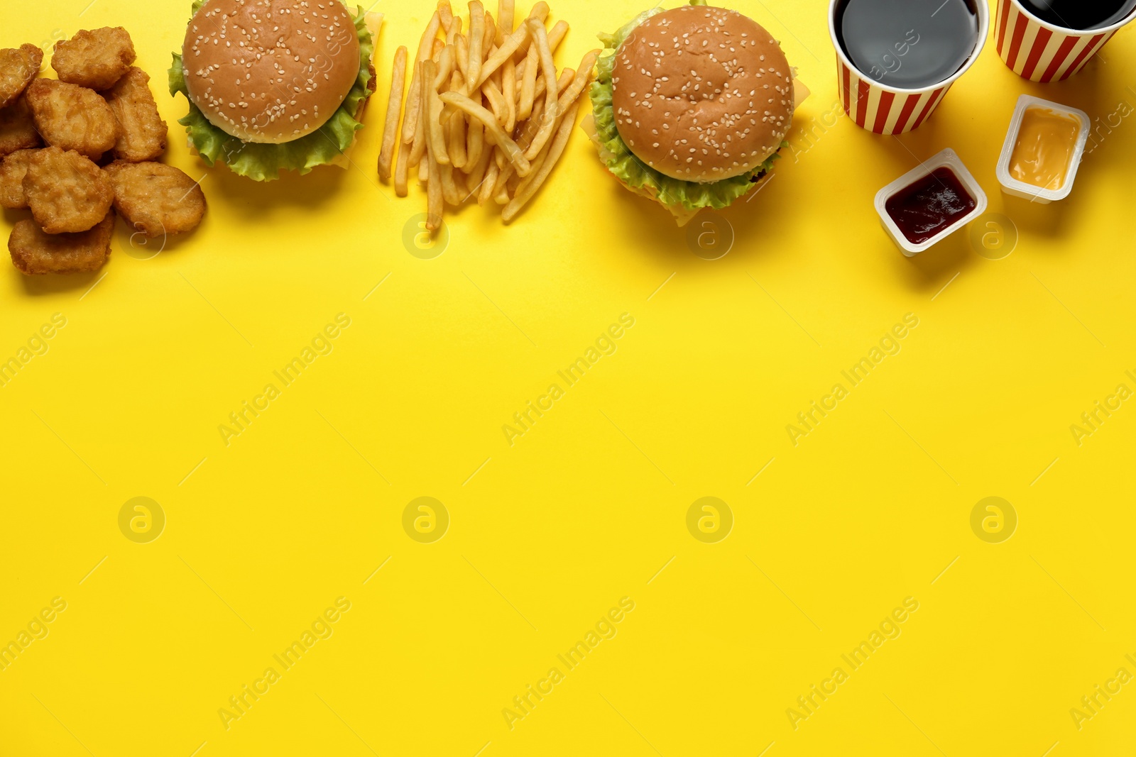 Photo of Flat lay composition with delicious fast food menu on yellow background. Space for text