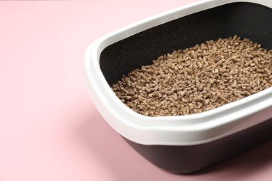 Photo of Cat litter tray with filler on pink background, closeup
