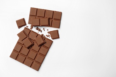 Photo of Delicious broken chocolate bar on white background, flat lay. Space for text