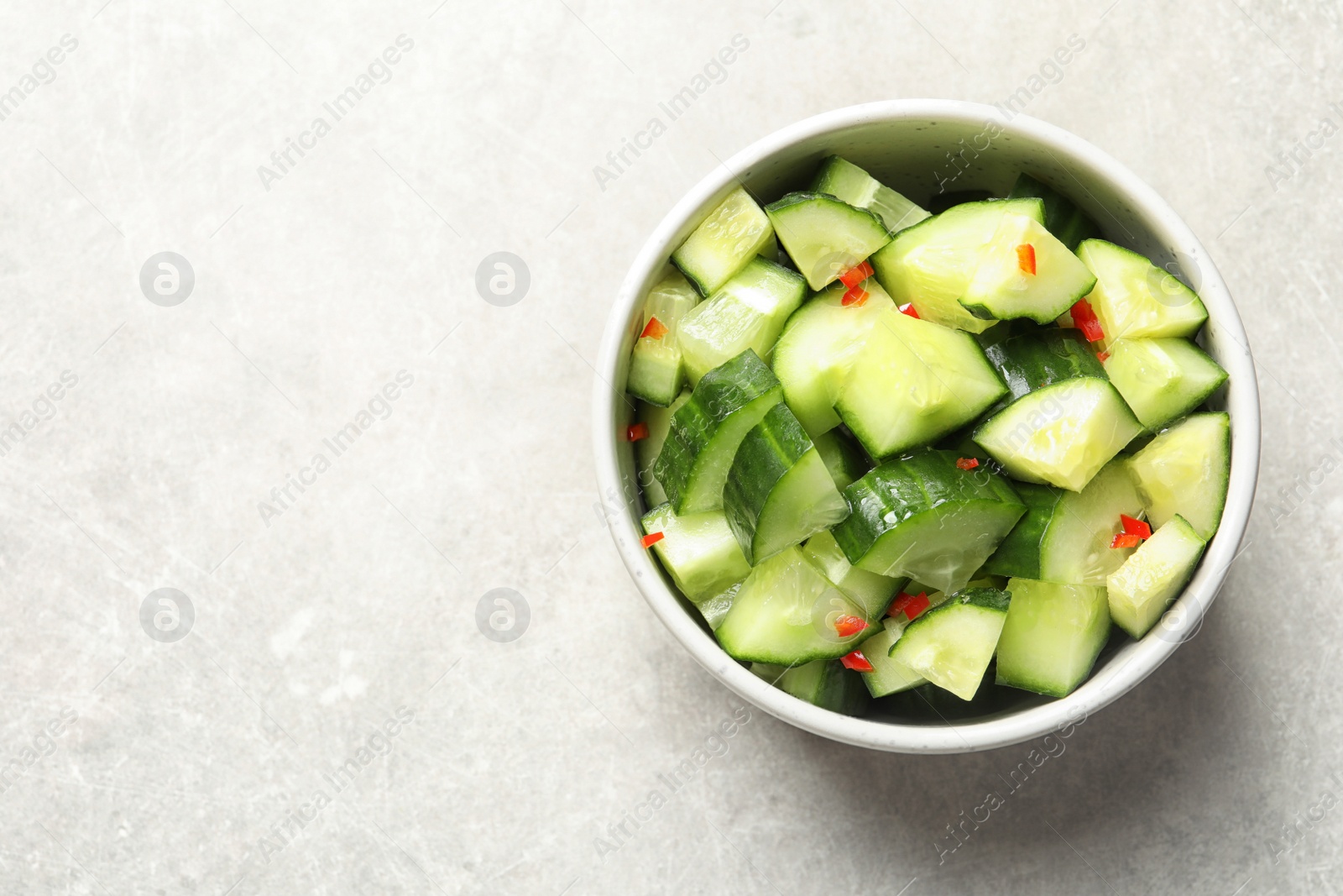 Photo of Delicious cucumber salad in bowl on grey background, top view. Space for text