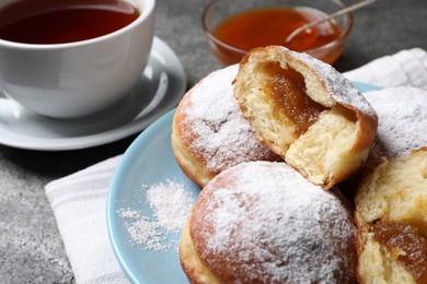 Delicious sweet buns with jam and cup of tea on table, closeup