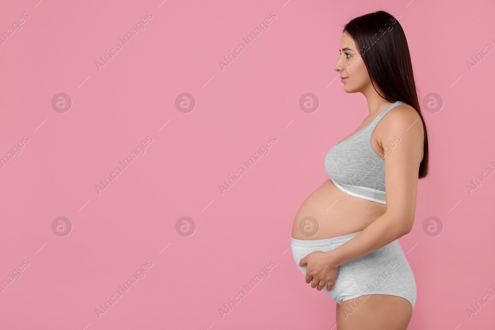 Photo of Beautiful pregnant woman in comfortable maternity underwear on pink background, space for text