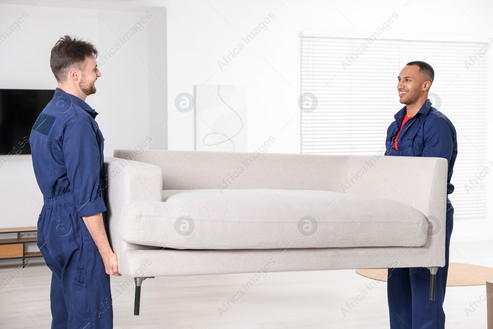 Photo of Male movers carrying sofa in new house