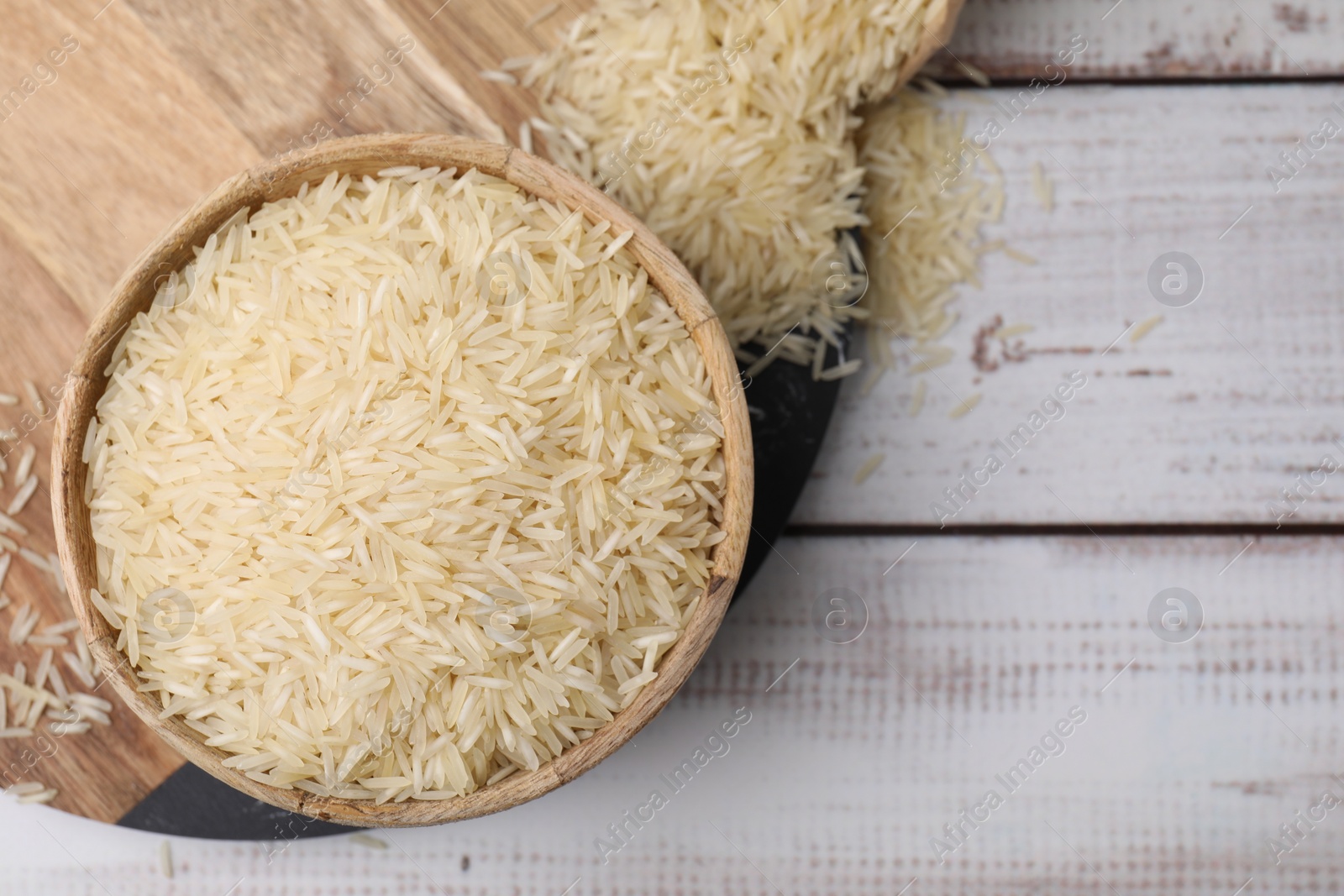 Photo of Raw rice in bowl on light wooden table, top view. Space for text