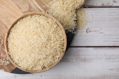 Raw rice in bowl on light wooden table, top view. Space for text