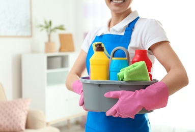 Photo of Woman with basin of detergents in living room, closeup. Cleaning service