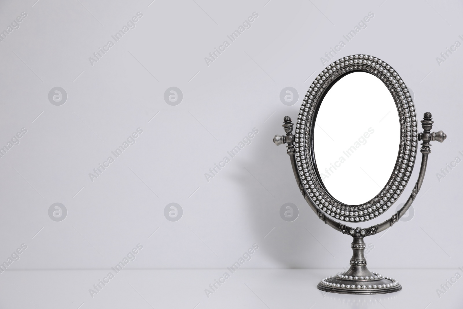 Photo of Silver vintage mirror with stand on white background, space for text