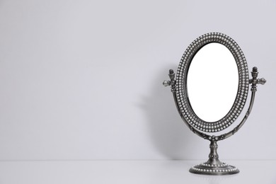 Photo of Silver vintage mirror with stand on white background, space for text