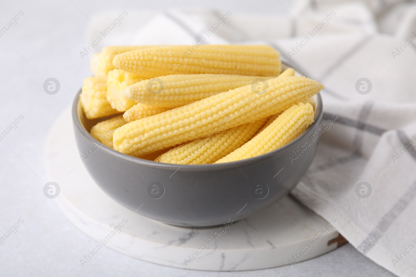 Photo of Tasty fresh yellow baby corns in bowl on white table