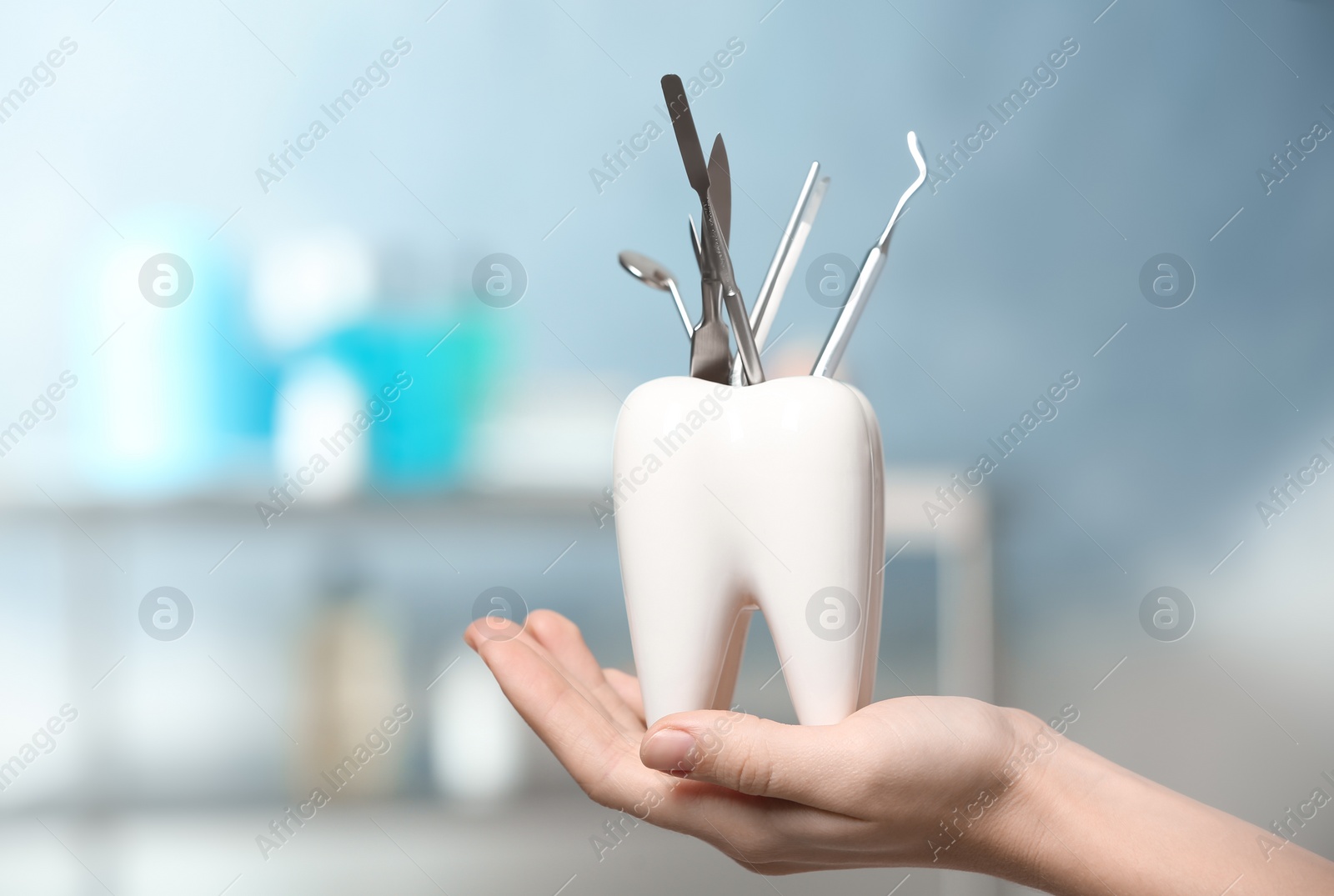 Photo of Dentist with tooth shaped holder full of professional tools in clinic, closeup