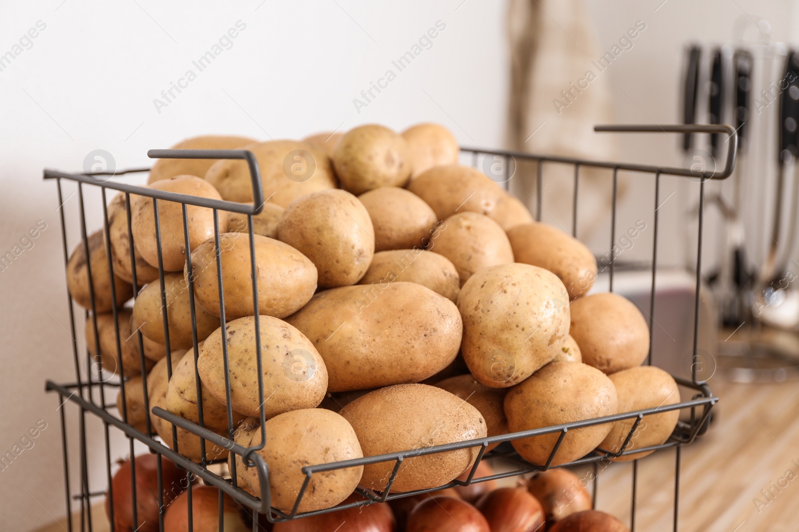 Photo of Container with potatoes and onions in kitchen. Orderly storage