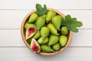 Cut and whole fresh green figs on white wooden table, top view