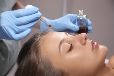 Cosmetologist applying serum on client's face in salon