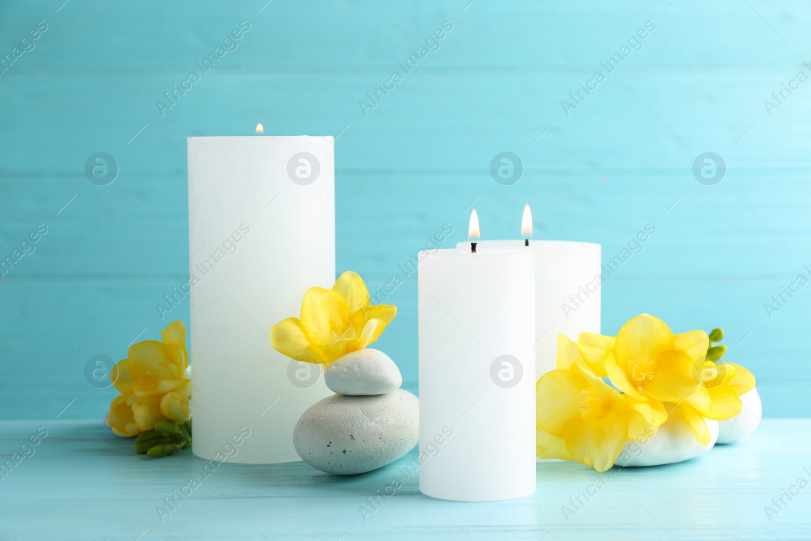 Photo of Composition of burning candles, spa stones and flowers on table