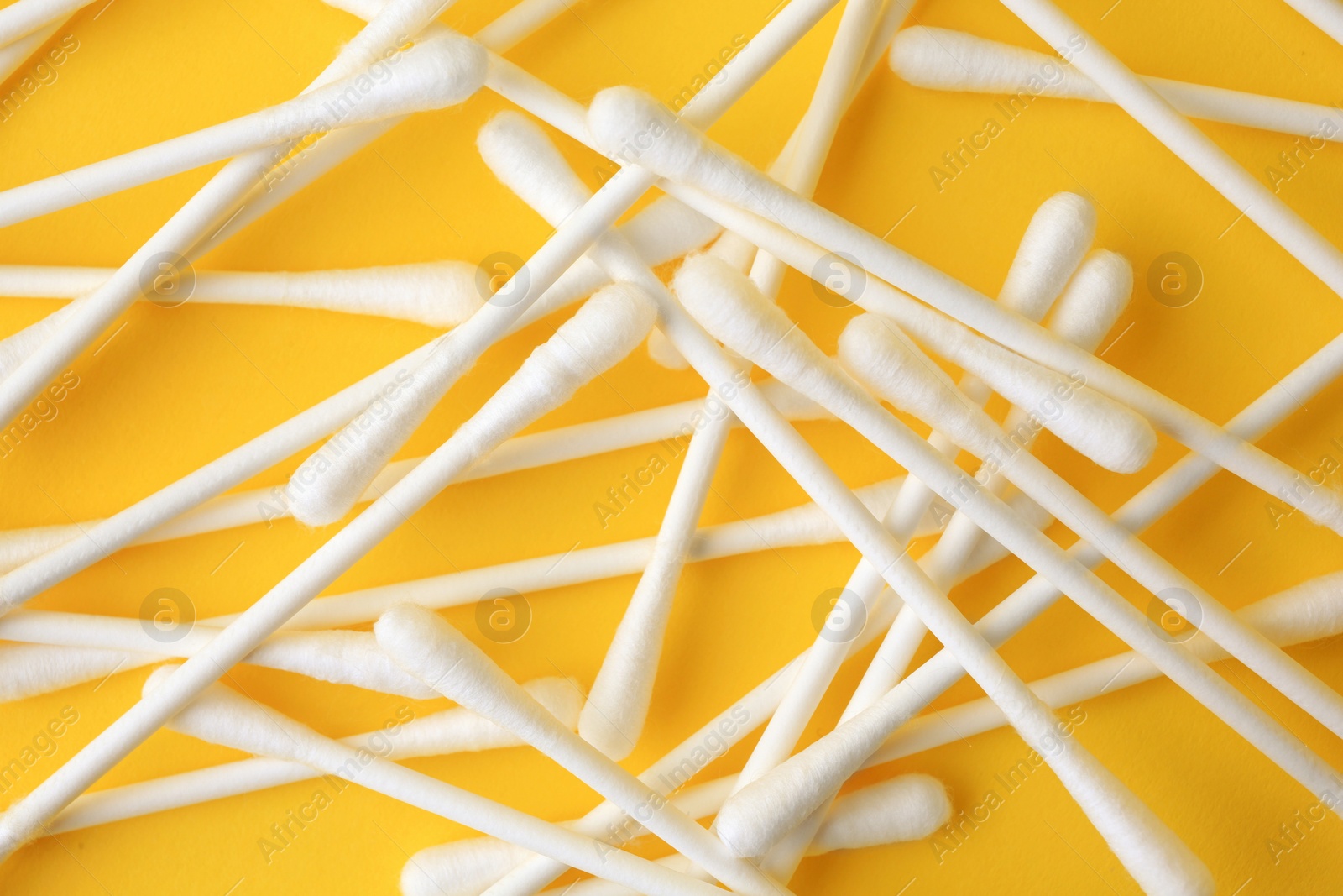 Photo of Many clean cotton buds on yellow background, flat lay