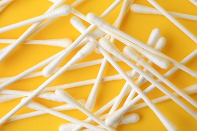 Many clean cotton buds on yellow background, flat lay