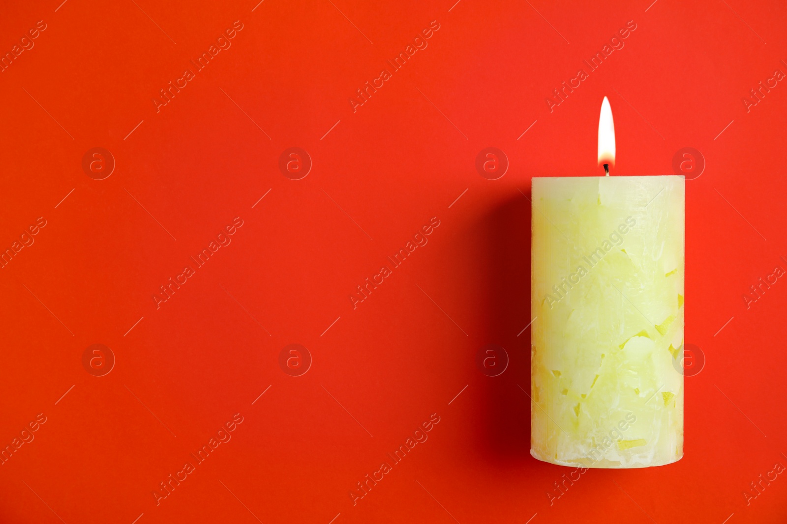 Photo of Alight wax candle and space for text on color background