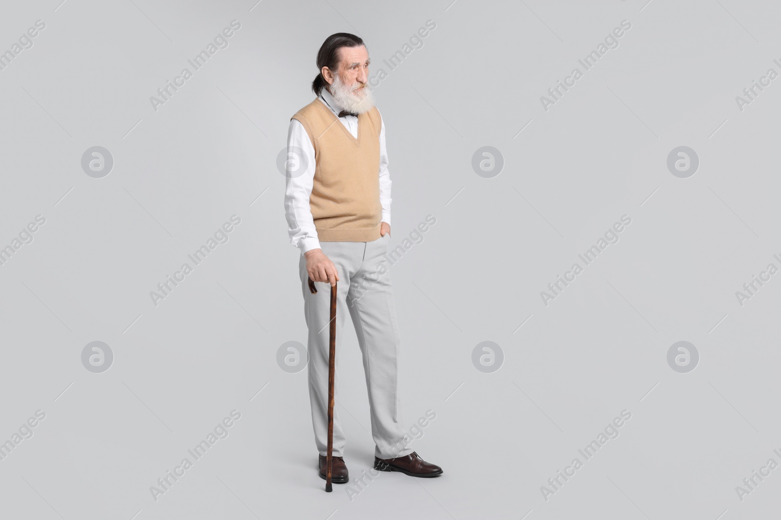 Photo of Senior man with walking cane on light gray background