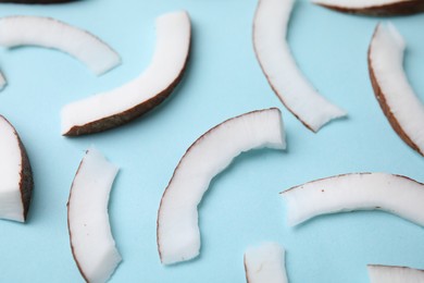 Photo of Fresh coconut pieces on light blue background, closeup