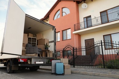 Van full of moving boxes and furniture near house