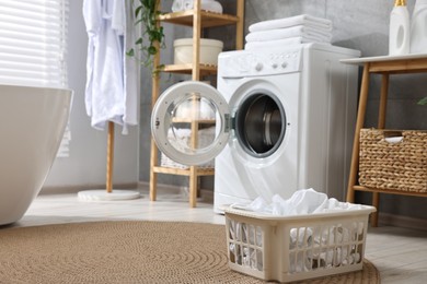 Photo of Basket with laundry near washing machine in bathroom