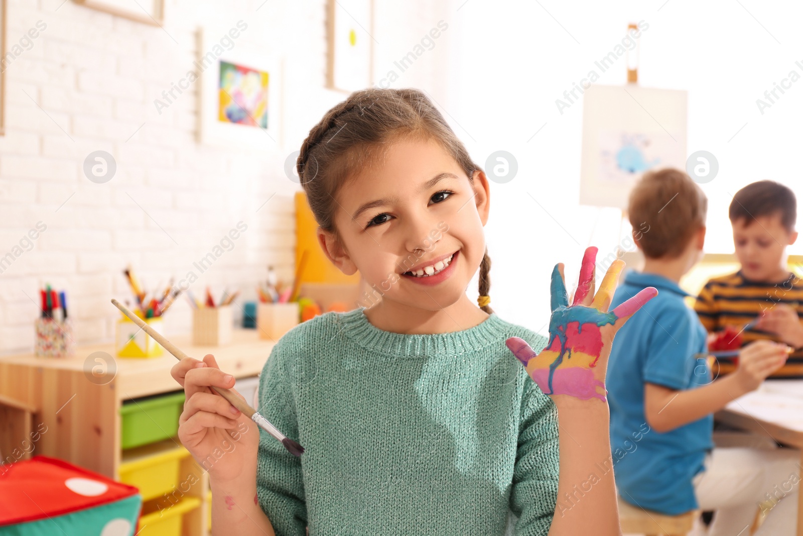 Photo of Cute little child with painted palm in room