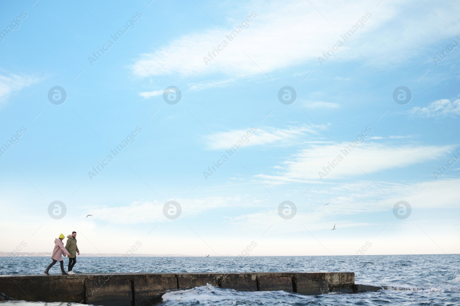 Photo of Lovely young couple walking on pier near sea