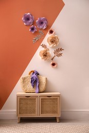 Photo of Cabinet near color wall with floral decor indoors