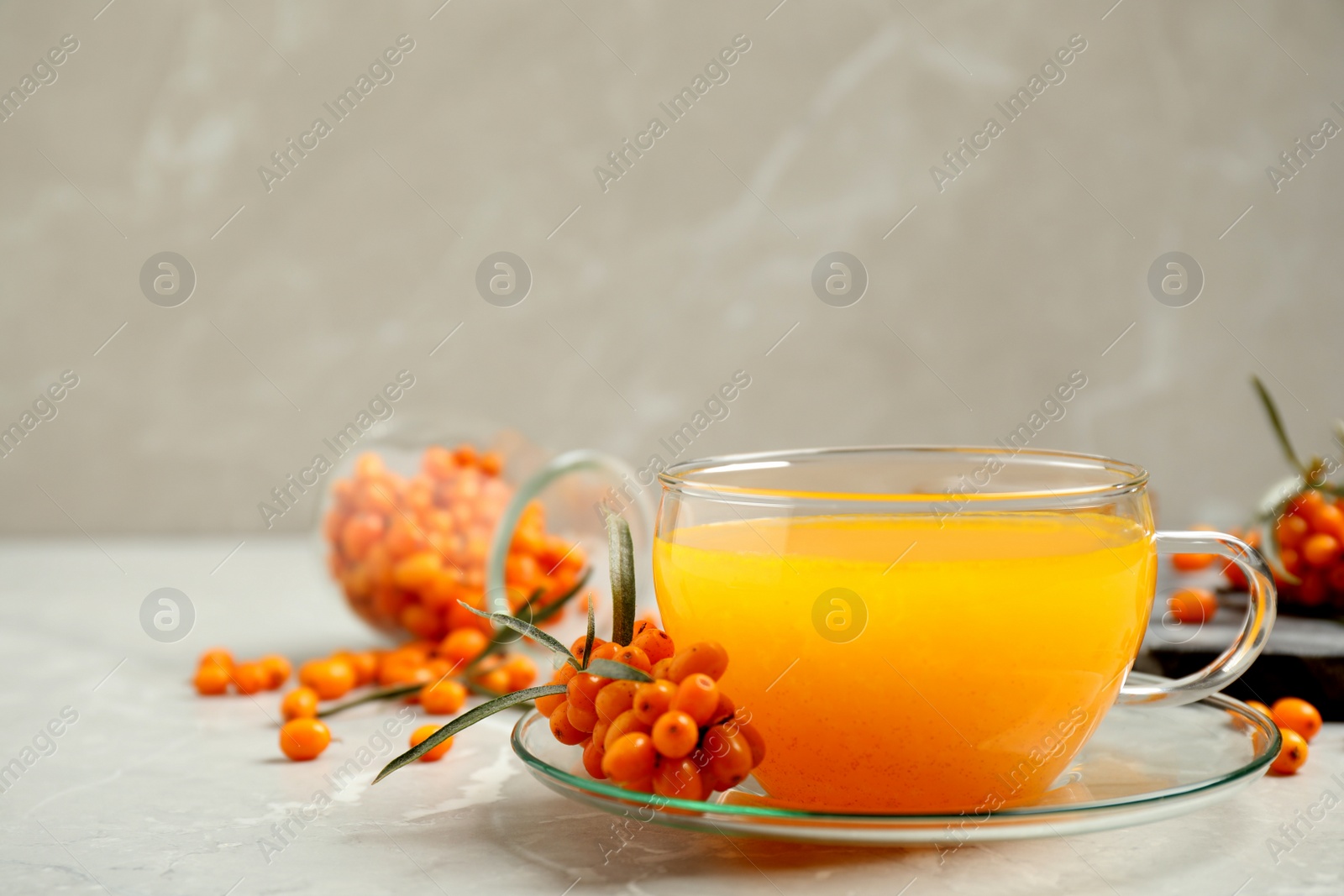 Photo of Delicious sea buckthorn tea and fresh berries on light grey table. Space for text